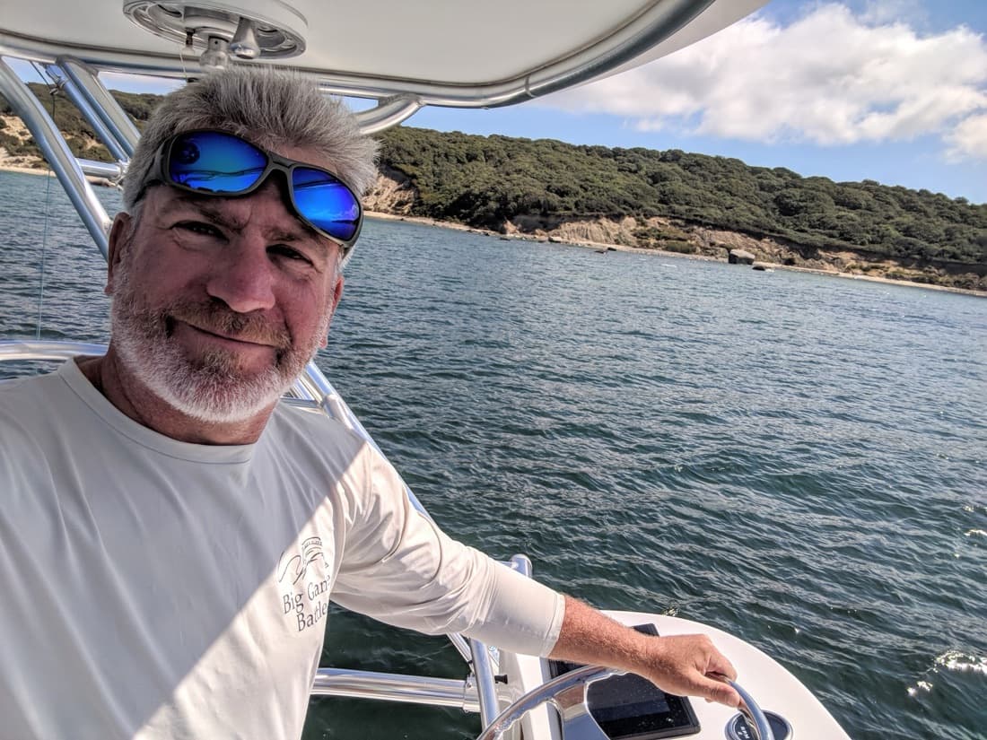 Dan Hermann at the helm of his center console off a wooded Massachusetts shoreline